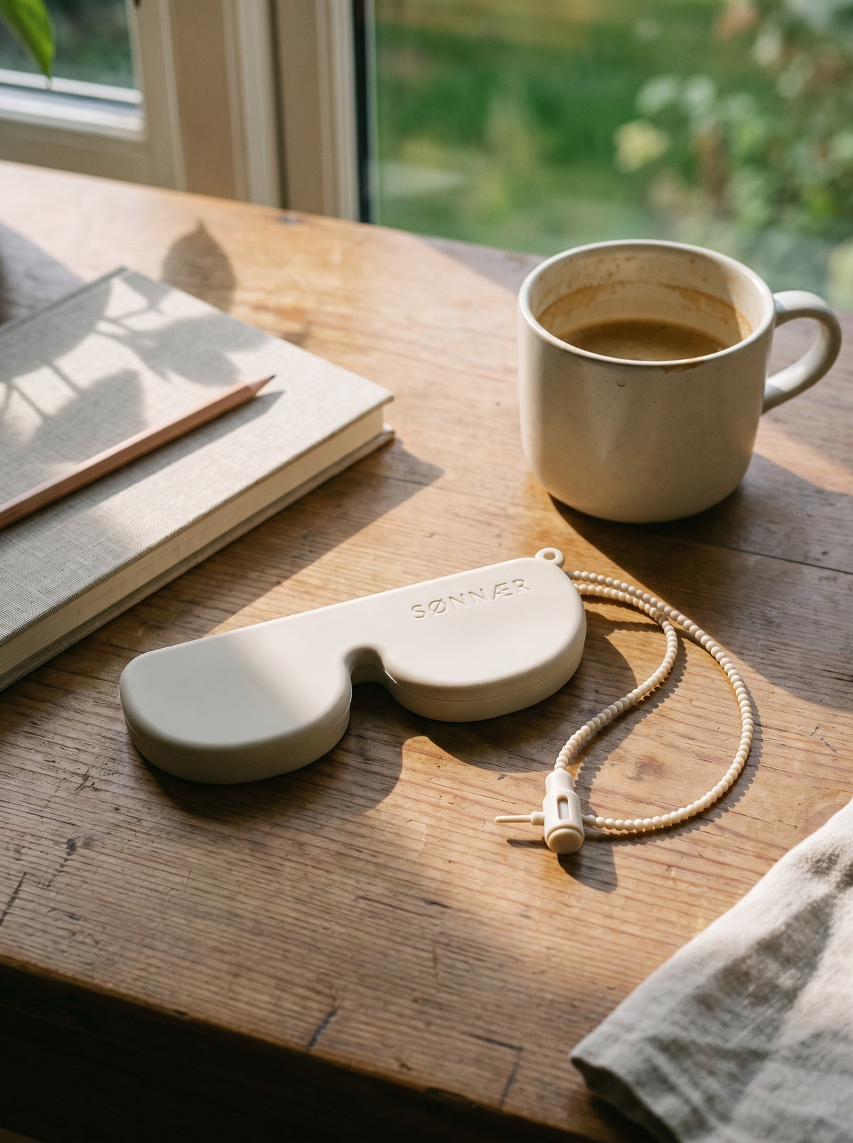 Cream SØNNÆR case on a wooden desk by a window
