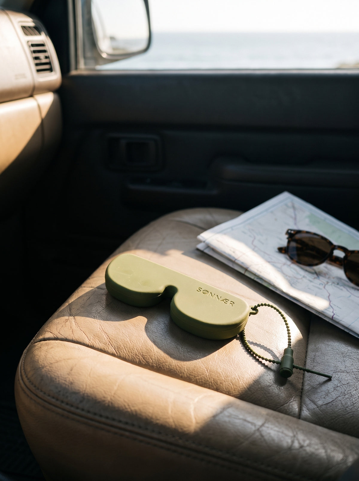 Olive SØNNÆR case on a leather car seat