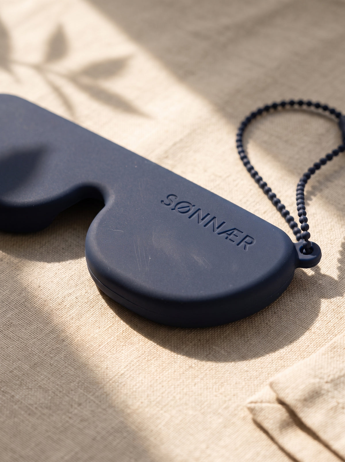 Close-up of the tonal laser-engraved SØNNÆR logo on the navy case