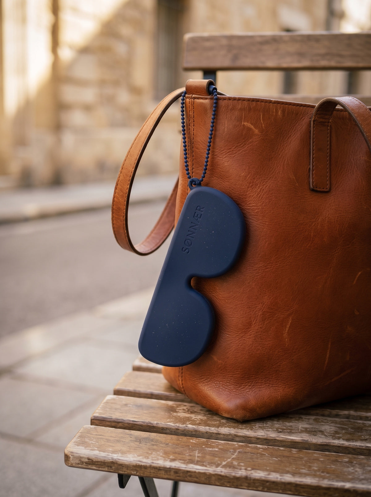Navy SØNNÆR case hanging from a leather tote